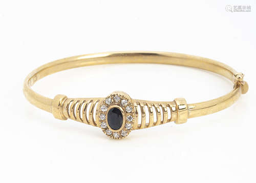 A gem set 9ct gold hinged bangle, with blue and white stones set in oval cluster with pierced