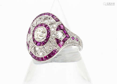 A ruby and diamond oval shaped dress ring, centred with an old cut diamond within a fan setting of