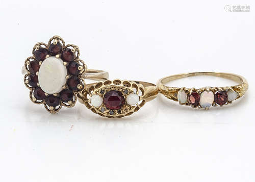 Two 18ct gold garnet dress rings, one set with white opals and rough cut diamonds centred with a