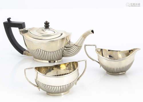 An associated late Victorian three piece silver bachelors tea set, oval with half fluted bodies,