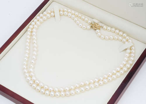 A double string of cultured pearls, of uniform size on a 9ct gold pierced clasp, 22cm together, with