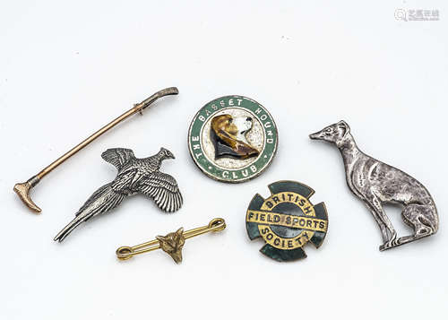 A collection of field sports badges and brooches, including a 9ct gold riding crop bar brooch, a