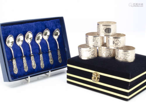 A set of six Middle Eastern white metal napkin rings, in box, together with a set of six far Eastern