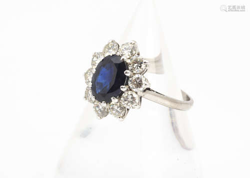 A sapphire and diamond 18ct white gold cluster ring, the oval mixed cut sapphire in claw setting