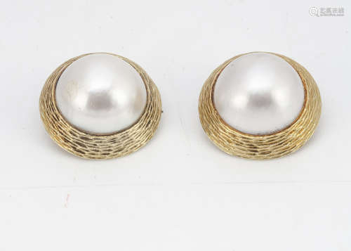 A pair of 14ct gold mabe pearl clip earrings, with textured tapered mounts marked 585 to reverse,