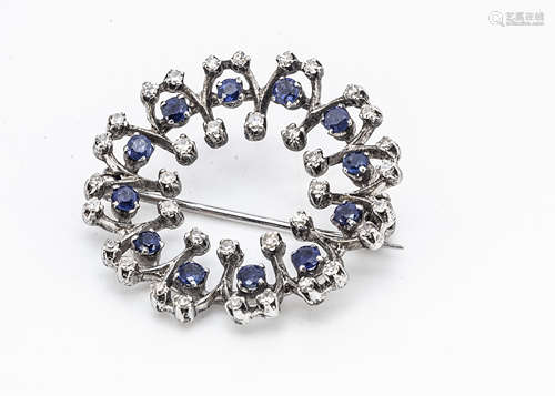 A contemporary white metal diamond and sapphire circular brooch, the mixed cut circular claw set