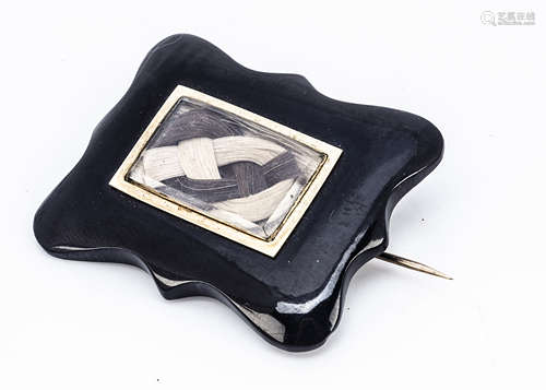 A 19th Century cased jet and plaited hair mourning brooch, the shaped jet mount centred with plaited