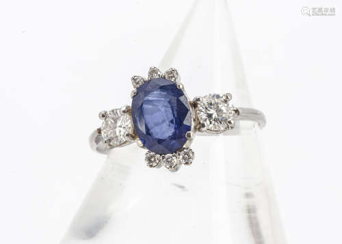 An 18ct gold sapphire and diamond dress ring, the oval mixed cut sapphire in four claw setting