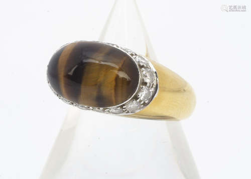 An 18ct gold tiger's eye and diamond dress ring, the cabochon tiger's eye of oval design with a side