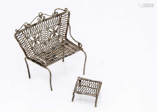 A continental white metal filigree miniature sofa and footstool, possibly from a dolls' house and