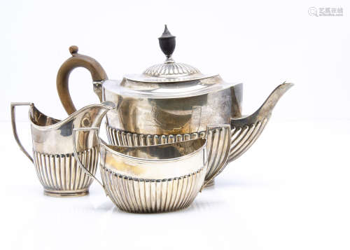 An associated Edwardian and later three piece silver tea set, all helmet shaped with fluted