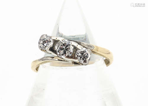 A diamond three stone crossover ring, the brilliant cuts in rubbed over claw settings on a yellow