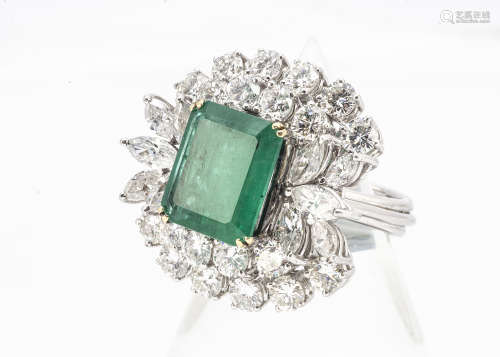 An impressive emerald and diamond cocktail ring, the central emerald cut in four claw setting