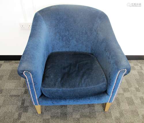 A contemporary tub arm chair, upholstered in a blue fabric with metal studding, raised on square