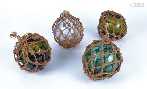 Four dumpy glass floats entwined in fishing ropes, three green, one a mauve / smoky grey hue,