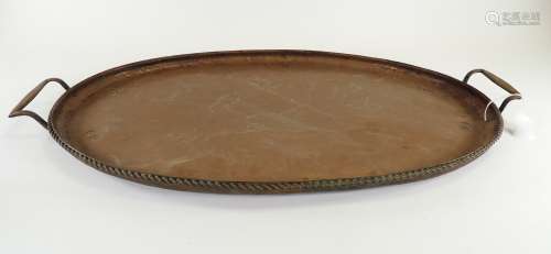 A twin handled oval copper tray, the cavetto with hammered Arts & Crafts effect, with a rope twist