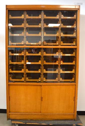 A 1930's oak haberdasher's cabinet, fitted interior with 32 comb jointed drawers, four sliding glass