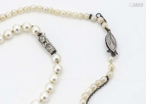 A string of uniform cultured pearls, the knotted strung white pearls with a pink overtone on an