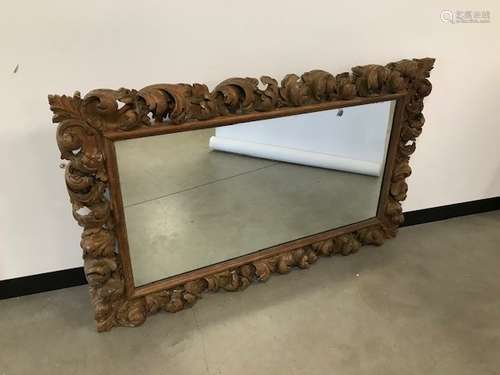 An antique carved pine frame, having rococo style scrolling foliage, inset with a glass mirror,