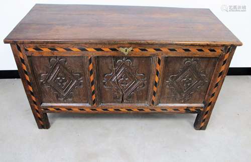 An antique oak panelled coffer, hinged plank top, the front having diamond shape carvings to