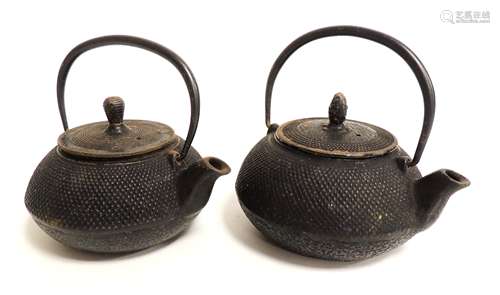 Two early 20th Century Chinese cast iron teapots, of squat compressed form with all over raised