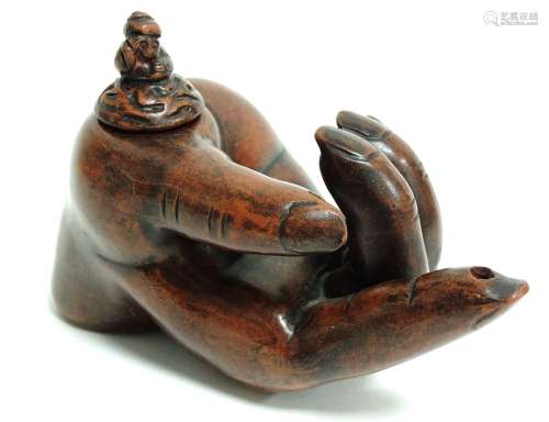 An earthenware oil lamp taking the form of a partially open hand with outstretched finger, the