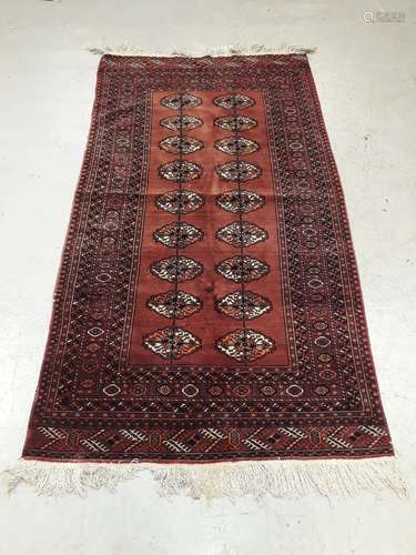 Old Middle Eastern Rug, a bordered geometric patterned red ground example with eighteen oval