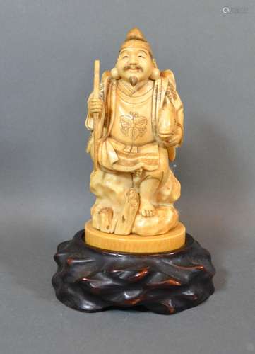 A 19th Century Japanese Carved Ivory Okimono in the form of a tradesman with hardwood stand 15cm