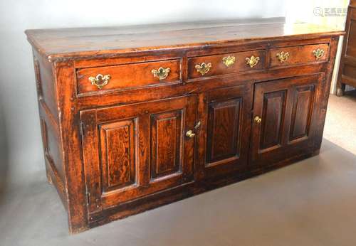 A George III Oak Dresser Base, the plank top above three frieze drawers and two cupboard doors