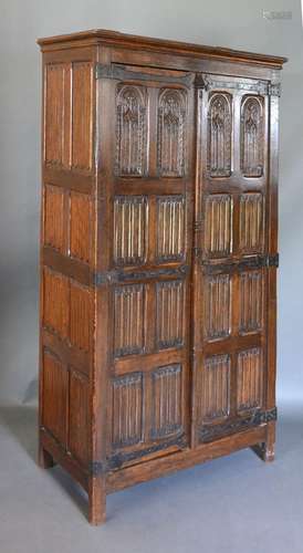 An Early 20th Century Oak Gothic Revival Hall Cupboard, the Gothic tracery and linen fold panel