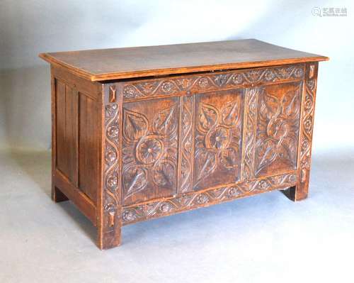 An 18th Century Oak Coffer, the hinged top above a three panel carved front flanked by stiles, 108