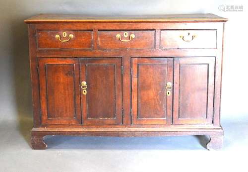 A George III Oak Dresser Base, the plank top above three drawers and four cupboard doors with