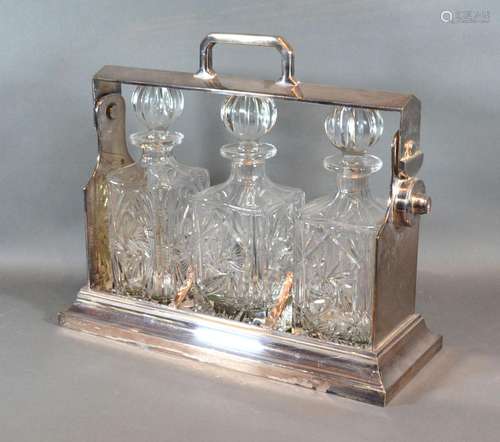 A Silver Plated Tantalus with three cut glass decanters and stoppers, 38 cms wide