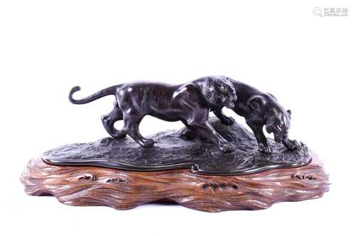 A Japanese bronze group of two tigers, Meiji period, naturalistically modelled prowling by the