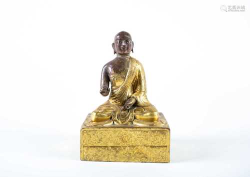 A Tibetan gilt bronze monk, 18th century, his face with traces of white enamel to the eyes and red