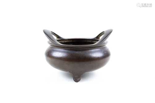 A Chinese bronze censer, possibly Ming, the body below a pair of swung handles, on three stub