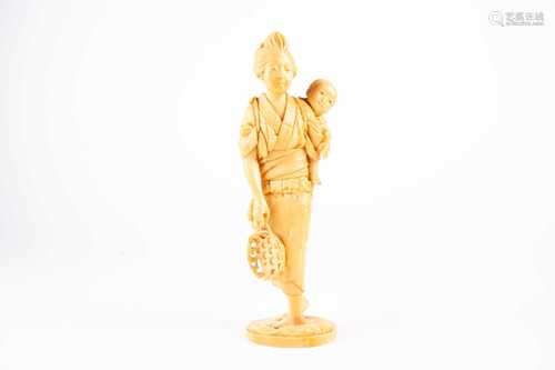 A Japanese ivory okimono, Meiji period, carved as a mother and child, a basket in her right hand,