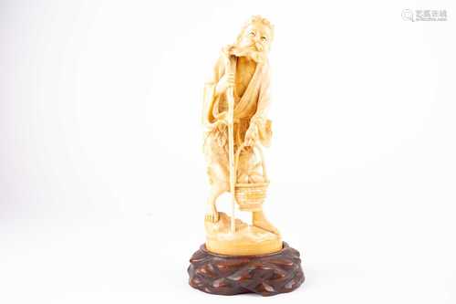 A Japanese carved ivory okimono of a man, Meiji period, wearing a robe with Artemesia leaves