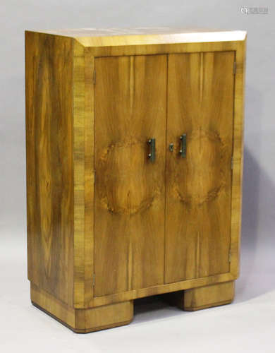 An Art Deco walnut bedroom cabinet with angular edges and Bakelite handles, height 122cm, width