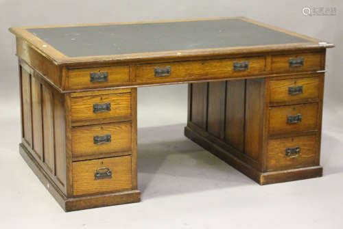 An early 20th century oak partners desk, the top inset with black leather above an arrangement of