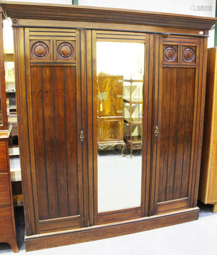 A late Victorian Aesthetic Movement walnut and ebonized three-section wardrobe, the interior