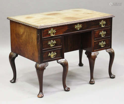 A George II mahogany kneehole desk, the crossbanded top with a carved edge above drawers and central