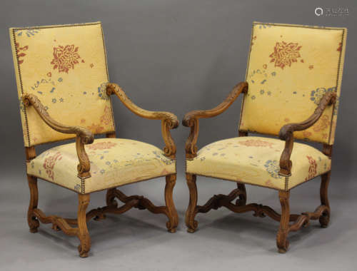 A pair of early 20th century French walnut framed armchairs, the seats and backs upholstered in a