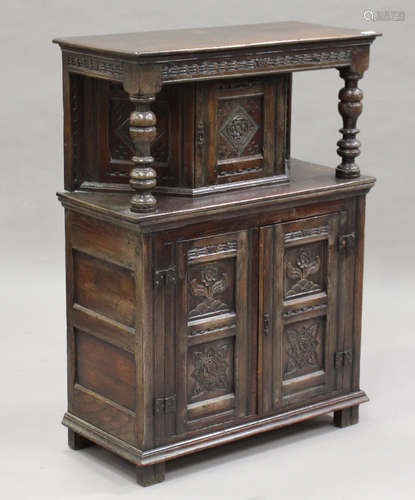 A 20th century Jacobean Revival oak side cupboard, fitted with three carved doors, height 112cm,