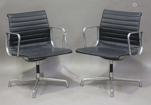 A pair of EA 108 cast aluminium and black leather revolving armchairs, made by Vitra and designed by
