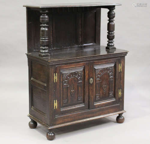 A 19th century Carolean Revival stained oak side cupboard, the shelf top above a pair of carved