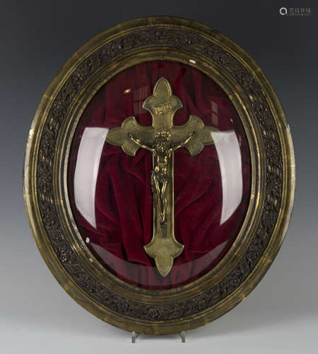 A late 19th/early 20th century gilt brass Corpus Christi, mounted within a glazed oval composition