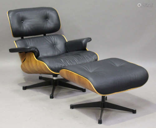 A modern black leather and walnut veneered plywood copy of an Eames lounge chair and matching