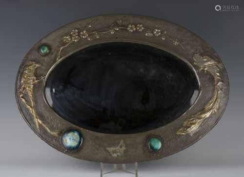 An early 20th century Arts and Crafts pewter mounted oval wall mirror, the frame worked with two