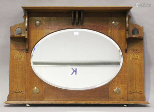 An Edwardian Arts and Crafts oak overmantel mirror, in the manner of Shapland & Petter, the oval